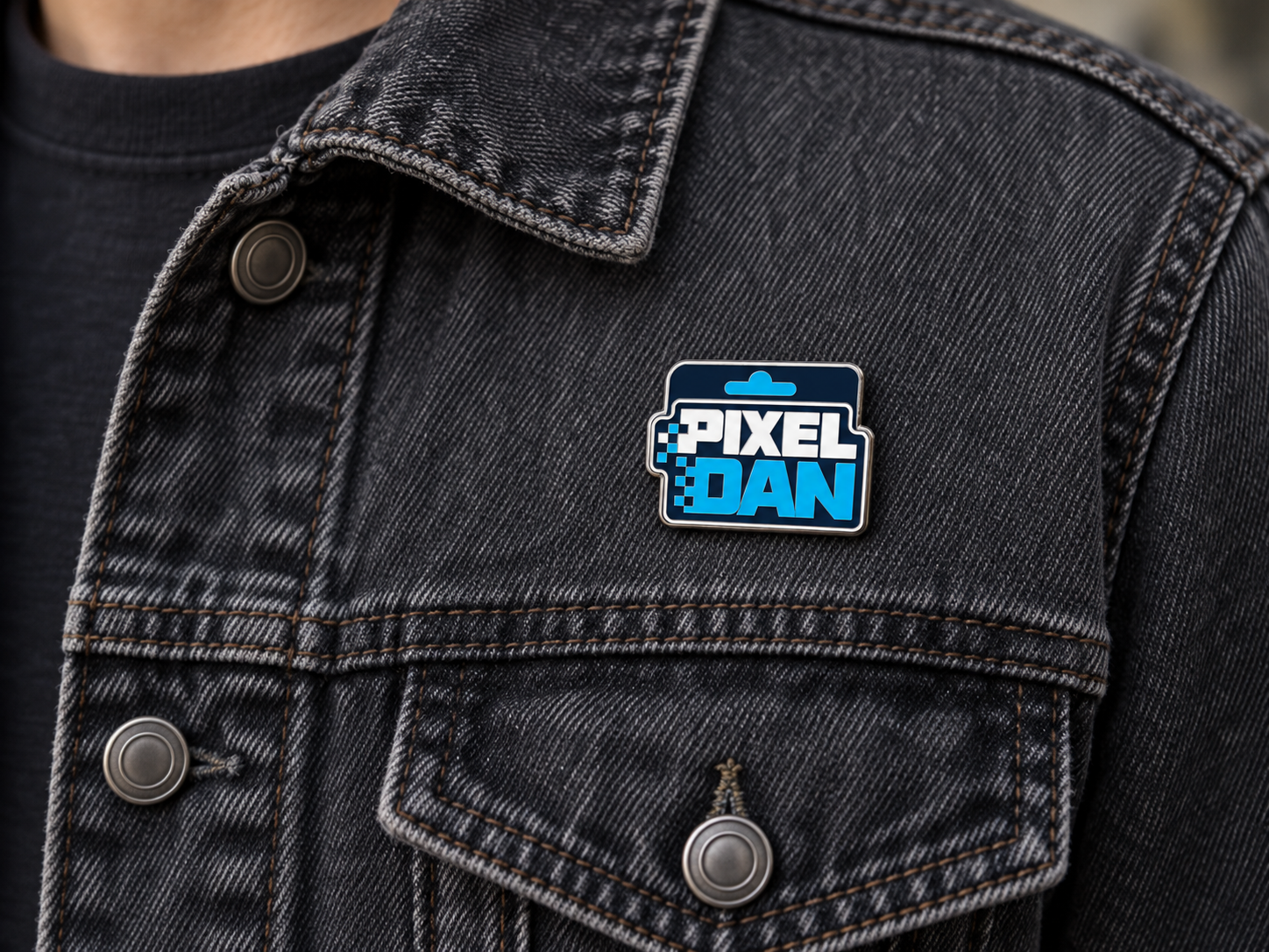 Small Pixel Dan enamel pin on a denim jacket, with the metal edge following the full navy card-back silhouette